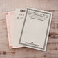Three vintage-style notepads stacked on a light wood background. The top notepad is cream with a black decorative border and the text 'BEFORE I CAN READ'.